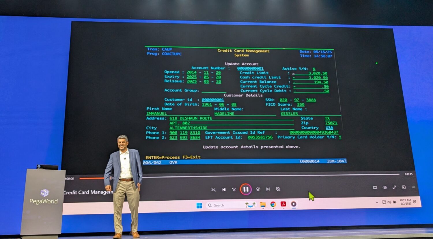 COBOL_legacy_Pega Een man staat op het podium naast een groot scherm met daarop een groen-zwarte interface van een creditcardbeheersysteem dat is gebouwd met Pega Blueprint, tijdens een presentatie.